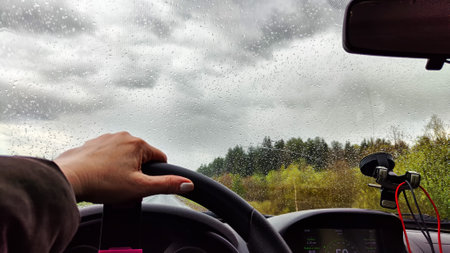 View from car windshield from the driver's seat and hand on the steering wheel of woman on during...