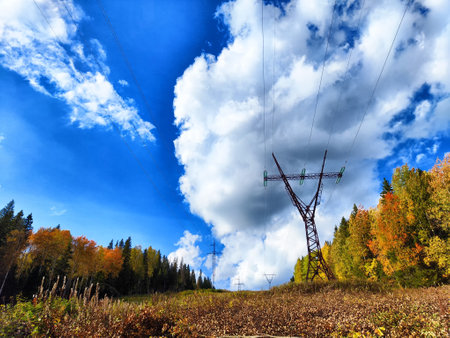 Power lines on a hill, hill or in the mountains against a blue sky with white clouds. Electric lines, towers, wires in nature landscapeの写真素材