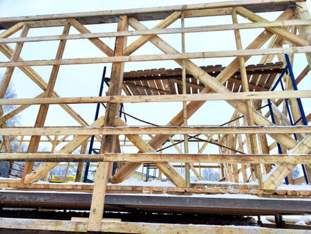 Wood frame house under construction, bare frame and walls with pile foundation, winter season