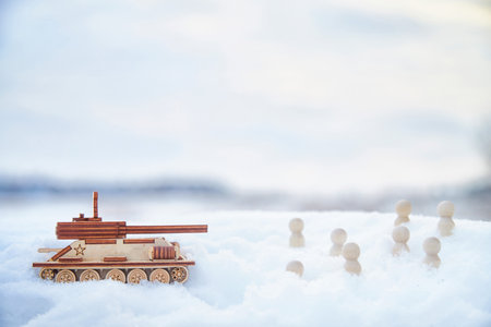 Wooden toy Russian tank T-34 and little men in the snow. Russia and Ukraine are at war in winter. Encirclement, retreat, attack, victoryの写真素材