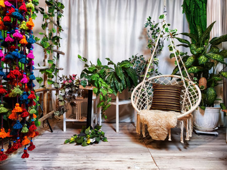 Modern cozy beautiful room with a braided rope macrame chair, green plants and a window with...
