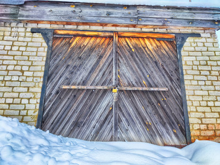 Old wooden gate in brick garage and white snow. Background, texture and locationの写真素材