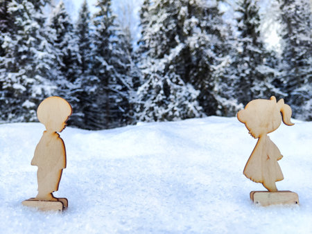 Wooden toys of boy and girl on white snow. Couple in love on Valentine's Day in February. Love in cold world and forest backgroundの写真素材