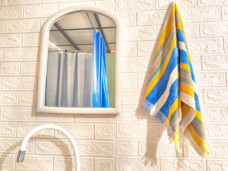 White wall with striped yellow and blue towel, mirror and faucet. Interior of modern bathroomの写真素材
