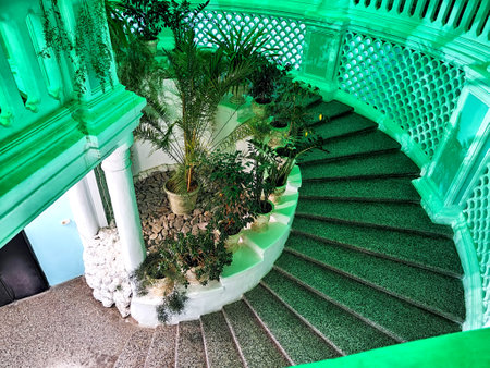Snail stone staircase with steps, white railings, green flowers and plants inside. Architecture. Abstract Background, location and patternの写真素材