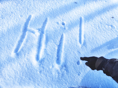 Inscription Hi, written on white background of the snow. Top view. Flat lay. New year and Christmas. Greeting morning, day, weather, sun and peopleの写真素材