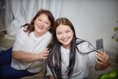 Fat funny funny adult mother and daughter posing, taking selfies indoors. Body positive, friendly...