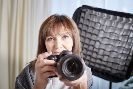 Senior old elderly woman with black camera with a large lens indoors in the studio. A professional...