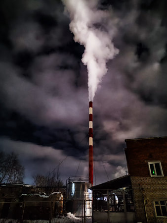 Winter night industrial landscape. Coal-fired power station with smoking chimneys against dramatic...