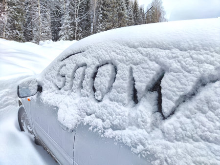 The car is covered with snow and the description snow on glass. Extreme snowfall, severe weather. Travel, tourism, travel in winterの写真素材