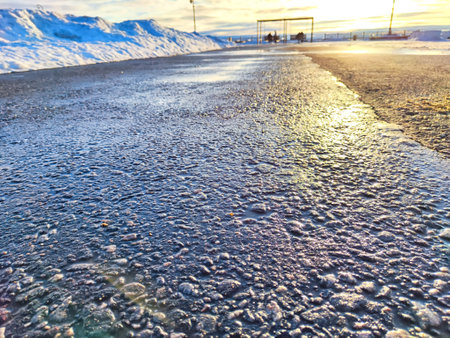 Sunlight Reflecting on a Wet Asphalt Road. Sun peeks over an ice covered road, casting glow on the textured surface. Background, texture, copy spaceの写真素材