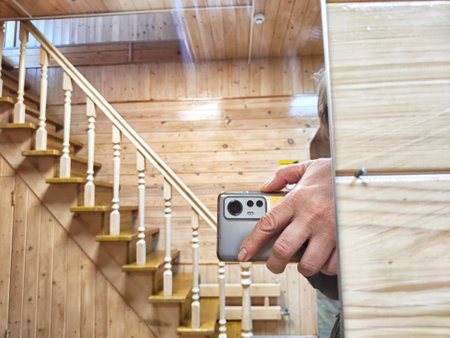 Close-up of a hand holding a phone to take a reflection selfie in mirror. Person Capturing Reflection in Mirror With Smartphone in Wooden Interiorの写真素材