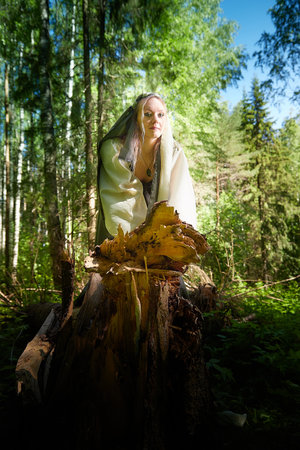 Beautiful seductive dryad. Pagan spirit of the forest. Portrait of beautiful dryad. Fairy who loves nature in beautiful green summer forest. Concept of environmental friendliness and caring for natureの写真素材