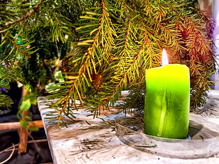 Candle burning amidst holiday decorations. Festive Candles Lighting Up Christmas-Adorned Room at Nightの写真素材