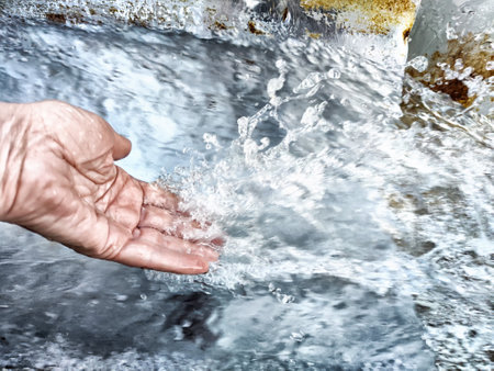 Close-Up of Hand Touching Flowing Water. Hand interacting with water in motionの写真素材