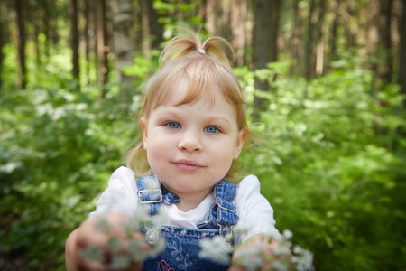 A pretty girl holds out a bouquet of flowers. Love for parents, for nature. Taking care of toddler...