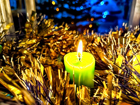 Candle burning amidst holiday decorations. Festive Candles Lighting Up Christmas-Adorned Room at Nightの写真素材