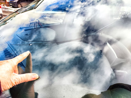 A hand points at a small chip and crack on car windshieldの写真素材