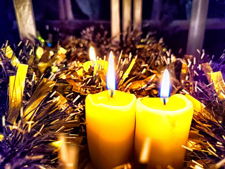 Candle burning amidst holiday decorations. Festive Candles Lighting Up Christmas-Adorned Room at Nightの写真素材