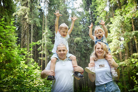 A man, woman, and child having fun and playing in the forest or park in summer or spring sunny dayの写真素材