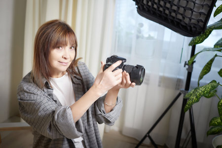 Senior old elderly woman with black camera with a large lens indoors in the studio. A professional...