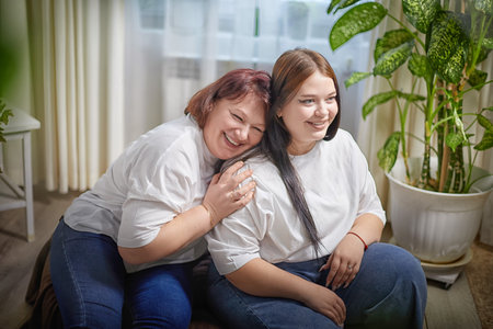 Happy Overweight family with mother and daughter in room. Middle aged woman and teenager girl having fun, joy, huggingの写真素材