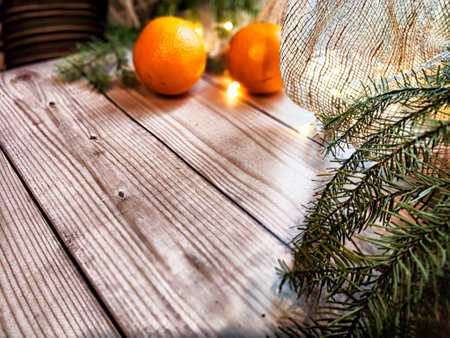 Festive decoration with bouquet and branches of spruce, bright glowing garlands, oranges on wooden background. Decor for Christmas and New Year. Abstract texture, frame, place for text and copy spaceの写真素材