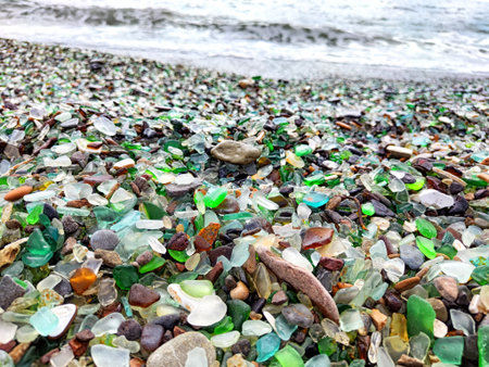 A beach with pebbles, glass and an incoming wave. Glass Bay in Vladivostok. Partial focus. A beach with pebbles, glass and an incoming waveの写真素材