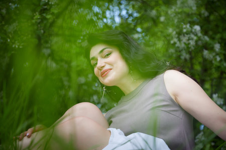 Joyous brunette woman near Blossoms of apple tree in a Spring Garden outdoors. Concept of face and...