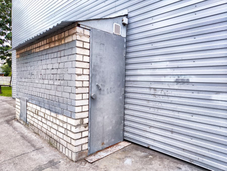 A weathered metal door in gray brick wall highlights urban architecture in a quiet areaの写真素材