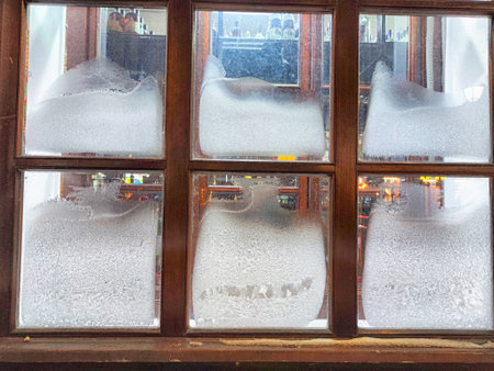 Frost collects on window glass, creating a delicate frost pattern as light shines from insideの写真素材