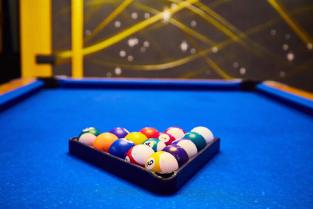 A set of colorful pool balls are ready to be racked on blue felt table