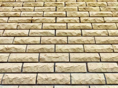 Beige bricks display a rough texture, arranged neatly in a pattern under natural light.