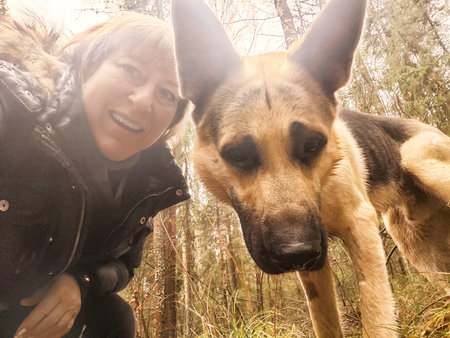 Adult girl or middle aged woman with shepherd dog in an autumn dayの写真素材