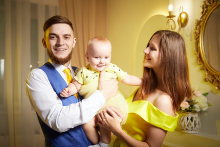 Family portrait with a young girl in a yellow dress in a decorated room with floral arrangements