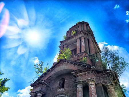 An old brick structure covered in vines stands against bright blue skyの写真素材
