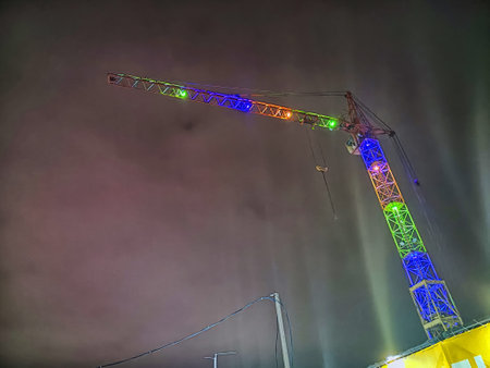 A brightly colored crane stands tall against the night sky, highlighting urban development and construction activities.の写真素材