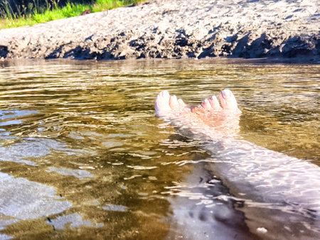 Feet float in lake water under bright, sunny skyの写真素材