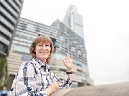 A middle-aged woman who is a tourist and blogger takes selfies near skyscrapers in Hong Kong on a tripの写真素材