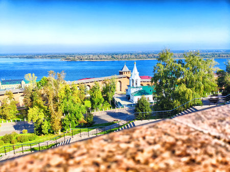 A panoramic view of a river with trees and buildings under a bright blue sky.の写真素材