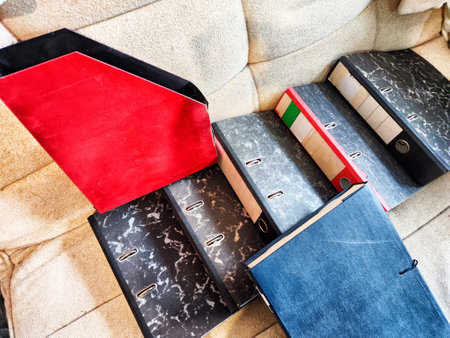 Multiple binders of different colors and sizes are displayed on beige couch, highlighting...
