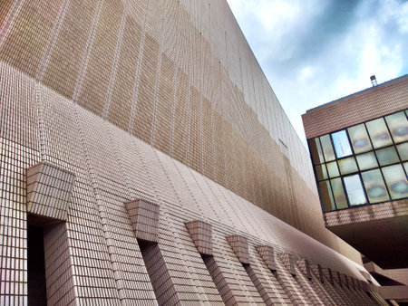 A close-up view of brick-patterned building facade with an overhanging concrete structure in Hong...