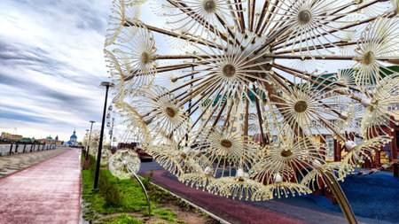 Dandelion-shaped sculptures add a whimsical touch to the urban park walkway under a cloudy sky.
