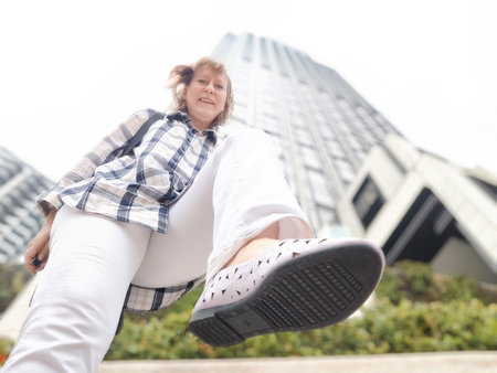 A middle-aged woman who is a tourist and blogger takes selfies near skyscrapers in Hong Kong on a tripの写真素材