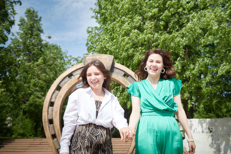 Portrait of happy girls in the park in summer. Female friends together. Young women pose together in sunny park during summer, enjoying time outdoorsの写真素材