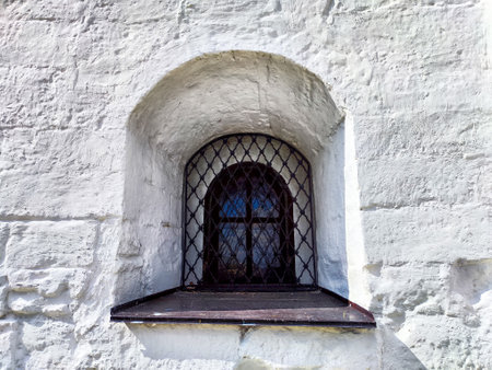 A rustic window featuring intricate lattice work set against a textured stone wall illuminated by sunlight.の写真素材