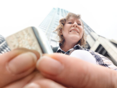 A middle-aged woman who is a tourist and blogger takes selfies near skyscrapers in Hong Kong on a tripの写真素材