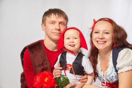 A family at a photo shoot in the style of the fairy tale Little Red Riding Hood. Father, mother, daughter in bright stylized costumes Little red capの写真素材