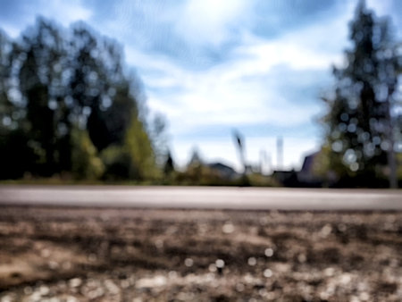 A blurry perspective of a road lined with trees under a bright blue sky on a sunny day hints at a tranquil rural setting.の写真素材