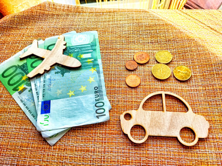 Travel symbols of an airplane and a car alongside Euro notes and coins illustrate transport cost comparison for travelers.の写真素材